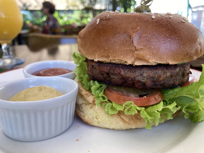 A foto mostra um hambúrguer e dois potes com condimentos