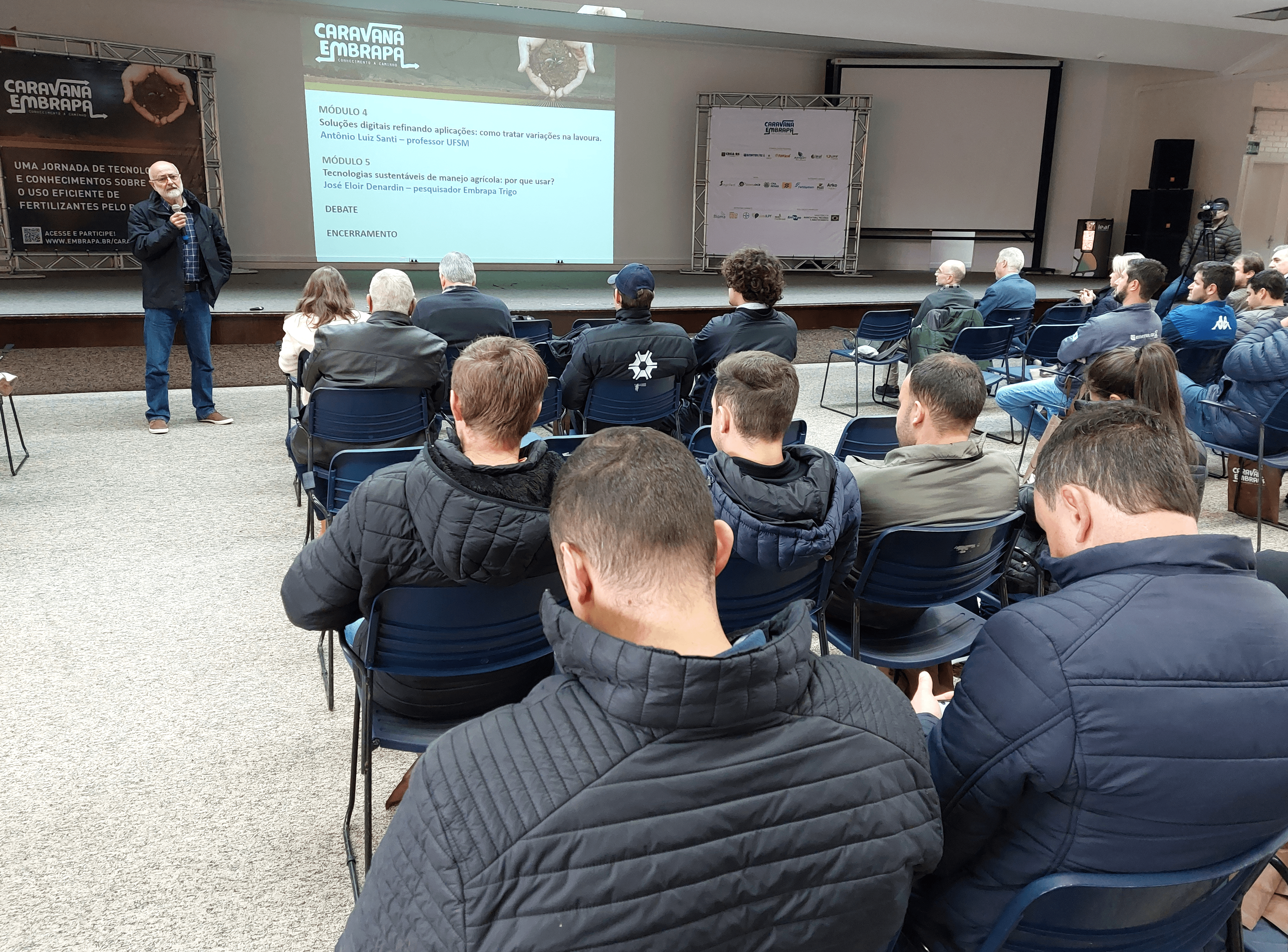 Foto de homem falando para o público durante evento em auditório.