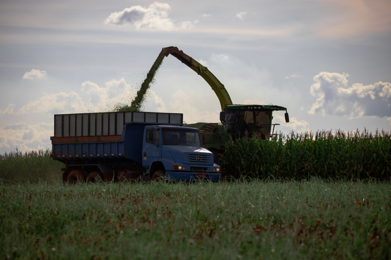 Foto de colheitadeira despejando grãos em caminhão.