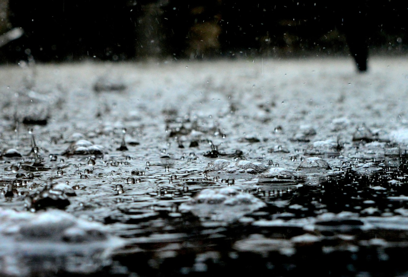 Foto de poça de água com chuva caindo.
