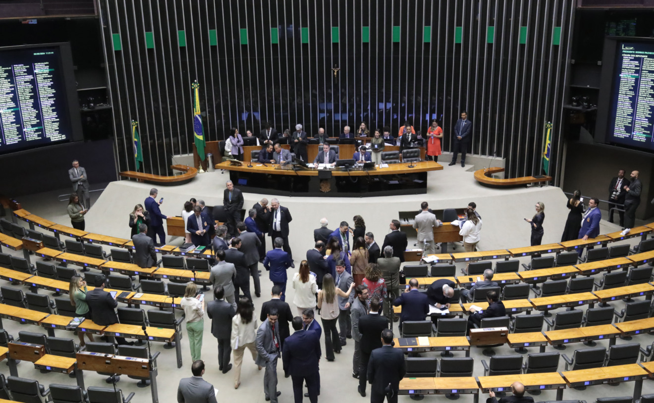Foto do plenário do Congresso Nacional com políticos sentados à mesa da presidência e os demais em pé na frente do plenário.