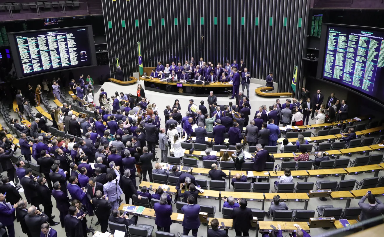 Foto de plenário da Câmara com deputados na mesa diretora e em frente dela.