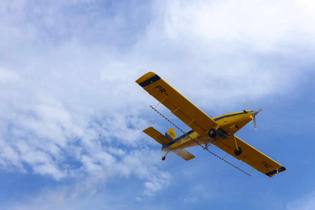 Foto de avião agrícola durante voo.