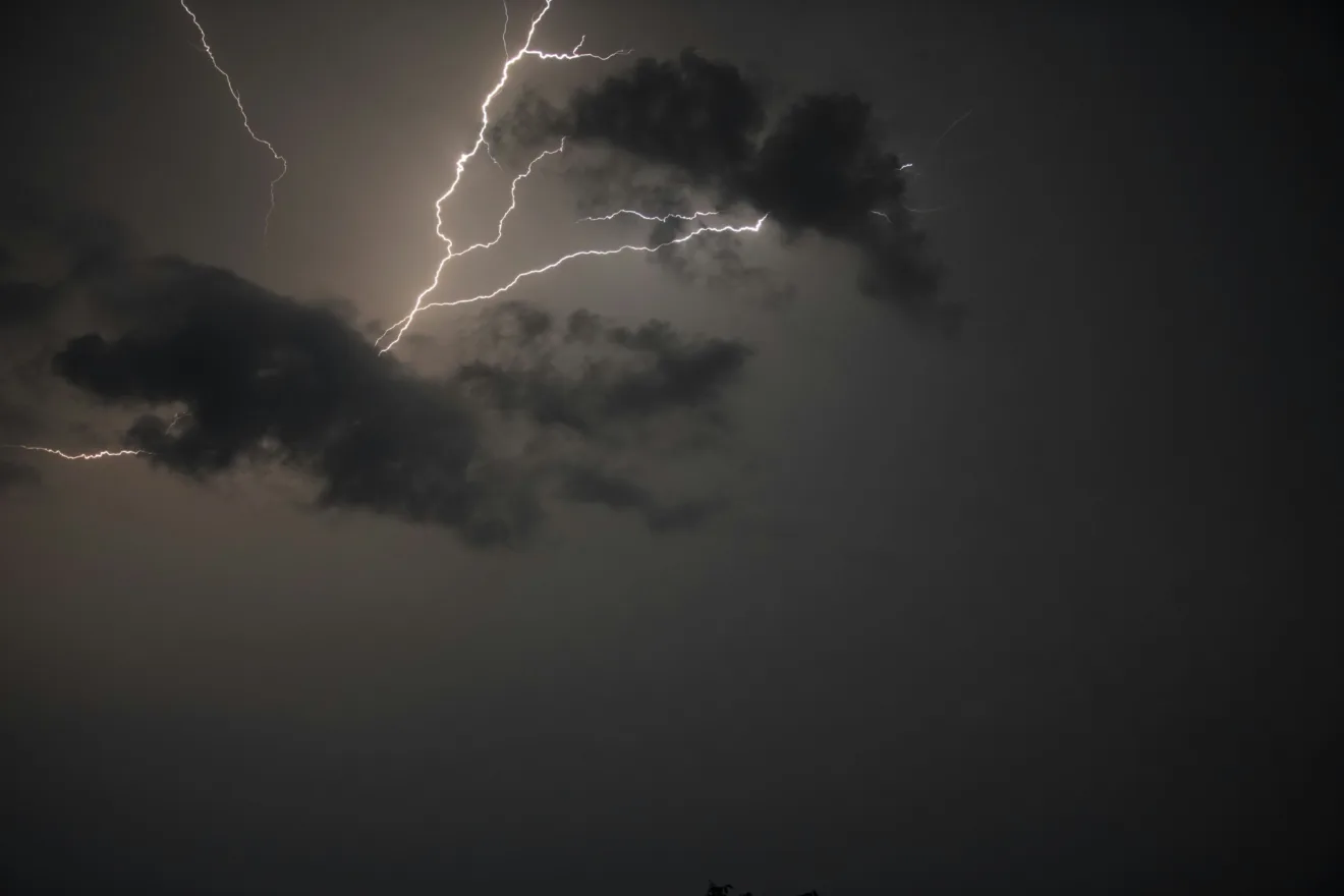 Foto de raio e nuvens escuras em céu acizentado.