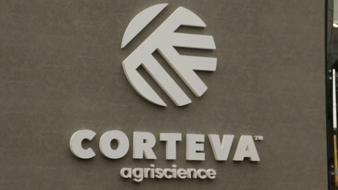 Foto de logo da Corteva Agriscience branca sobre parede cinza.