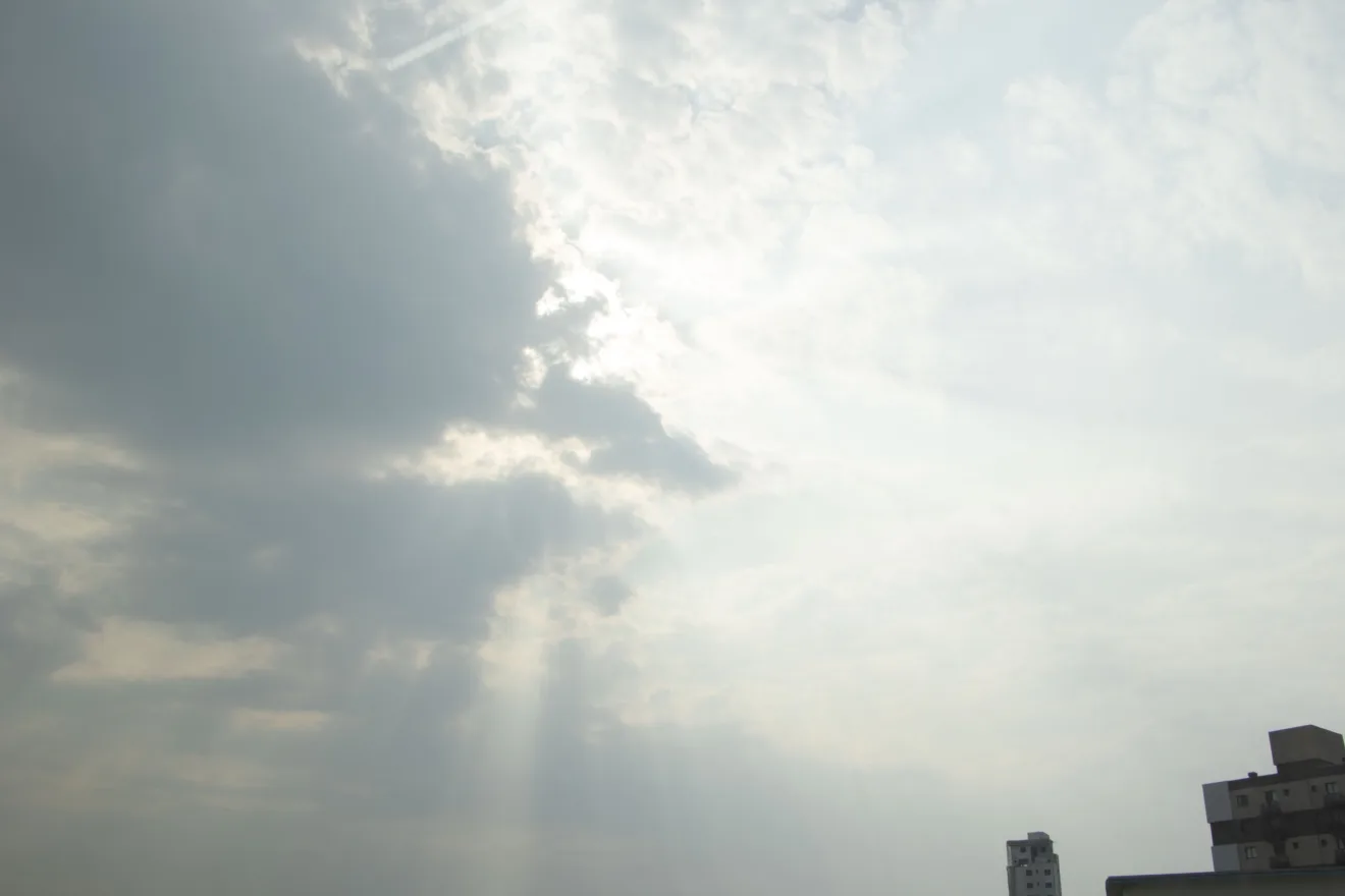 Foto de céu com tom acizentado e com nuvem escura cobrindo o sol.
