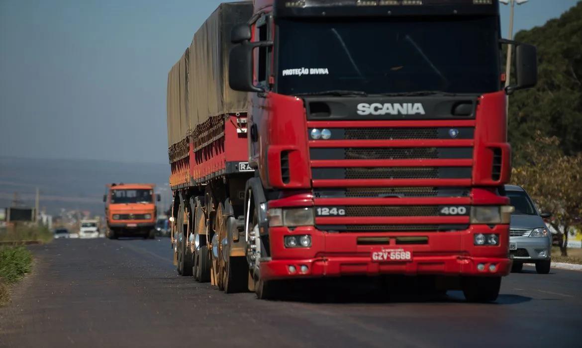 Foto de caminhão vermelho em rodovia.