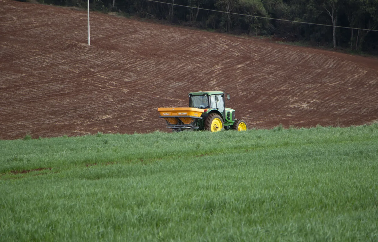 Foto de trator realizando aplicação nitrogenada em lavoura de trigo.