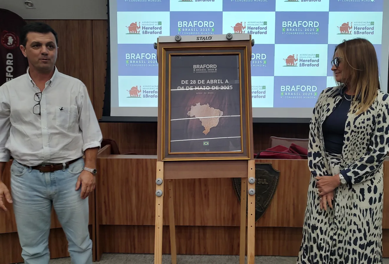 Foto de homem e mulher ao lado de placa que anuncia o Congresso Mundial Braford.