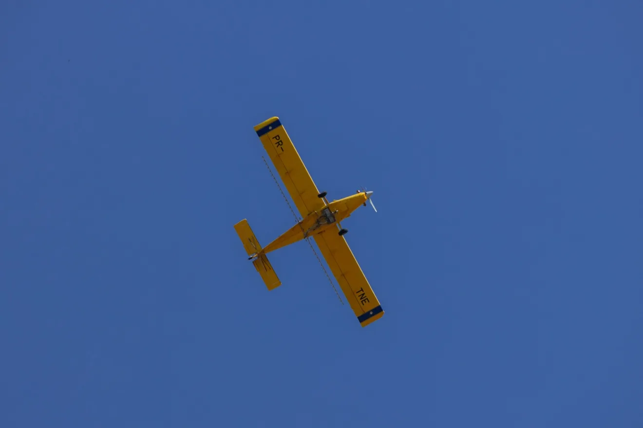 Foto de avião agrícola amarelo voando.
