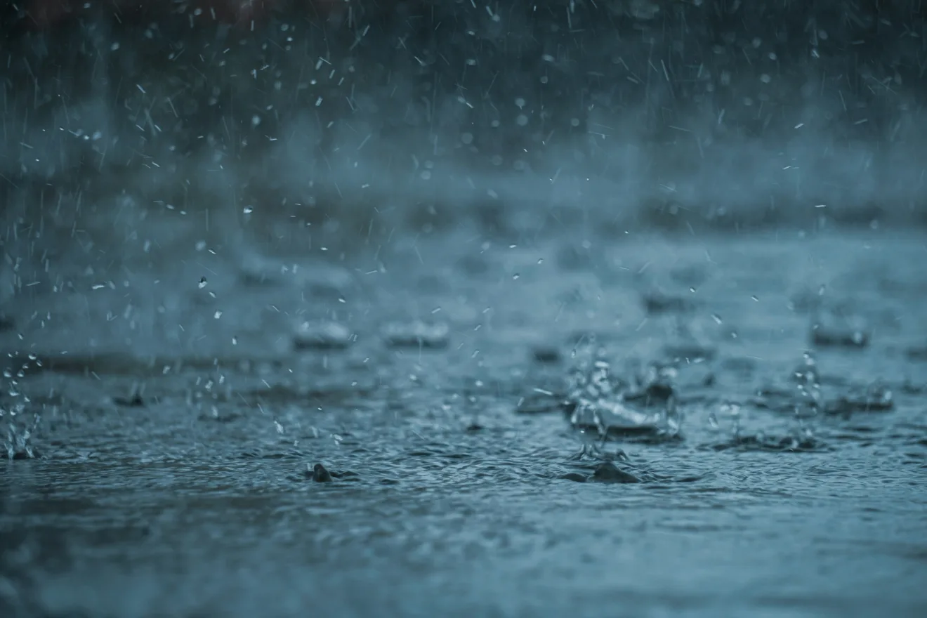 Foto de poça d'água com gotas de chuva caindo.