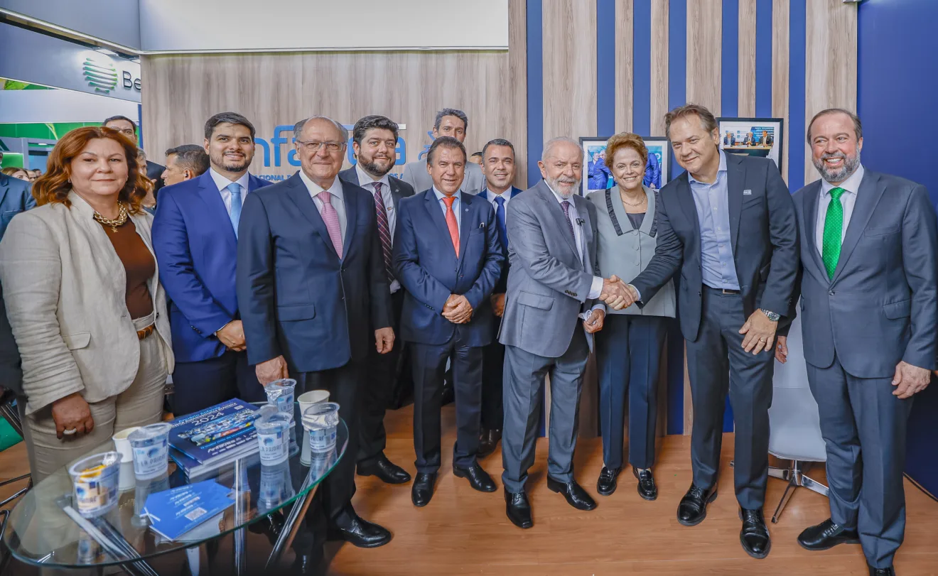 Foto de vários homens e duas mulheres lado a lado sorrindo. O presidente Lula está no centro e cumprimenta um dos homens.