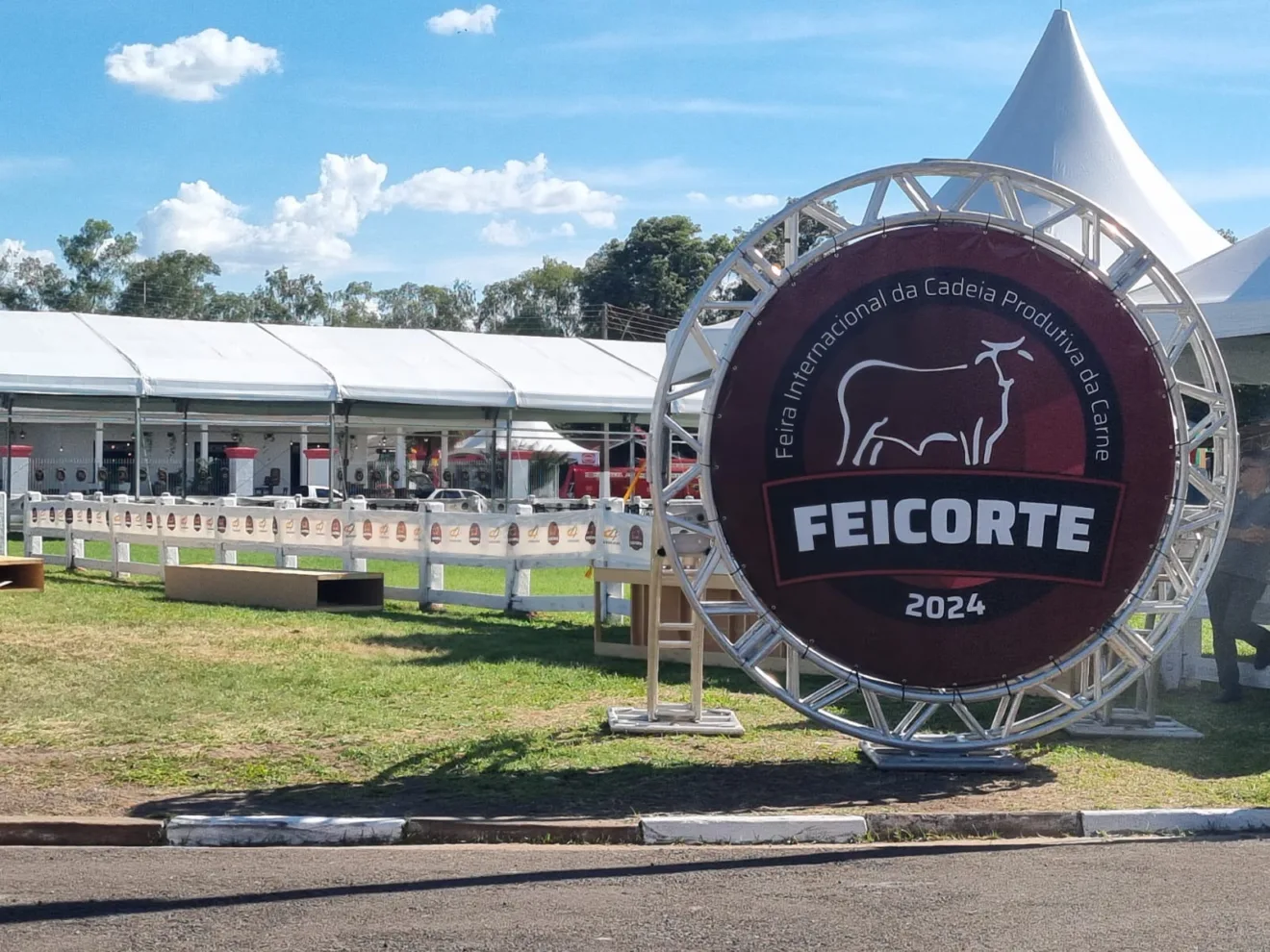 Foto de totten redondo com logo da Feicorte 2024 em fundo vermelho escuro.