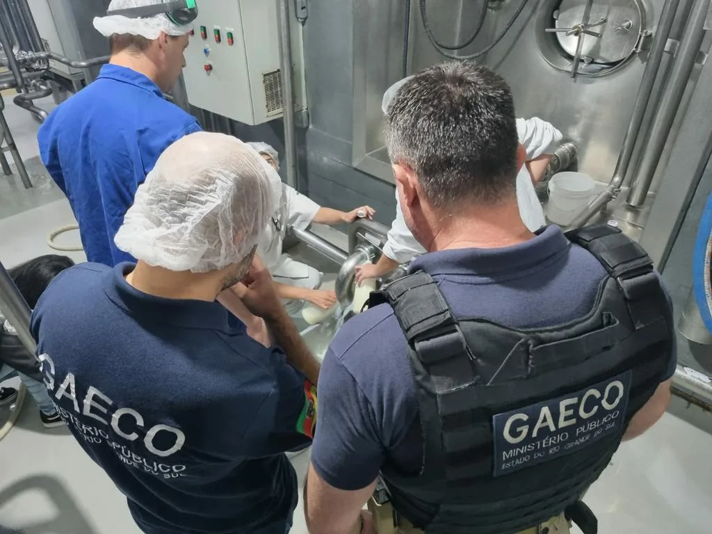 Foto de policiais da Geaco e funcionários de indústria de leite ao redor de tonel.