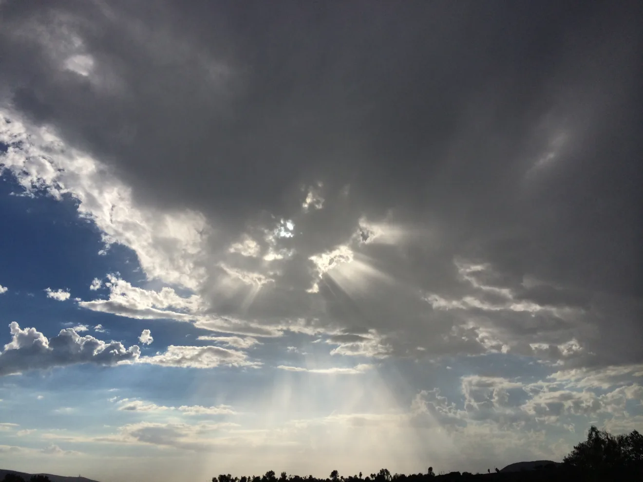 Foto de céu com nuvens escuras e raios de sol.