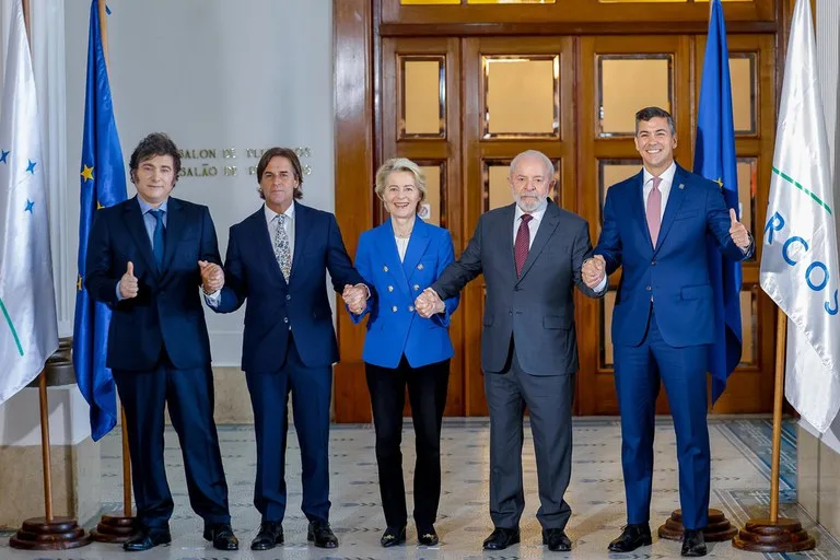 Foto dos presidentes Javier Milei, Luis Alberto Lacalle Pou, a representante da União Europeia (UE), Ursula von der Leyen e os presidentes Luiz Inácio Lula da Silva e Santiago Peña lado a lado de mãos dadas.