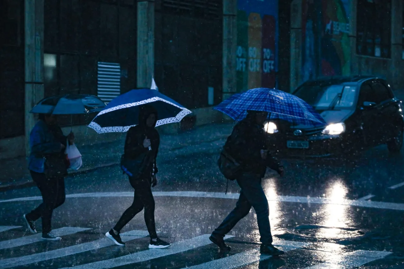 Pedestres passando pela faixa de pedestres na chuva.
