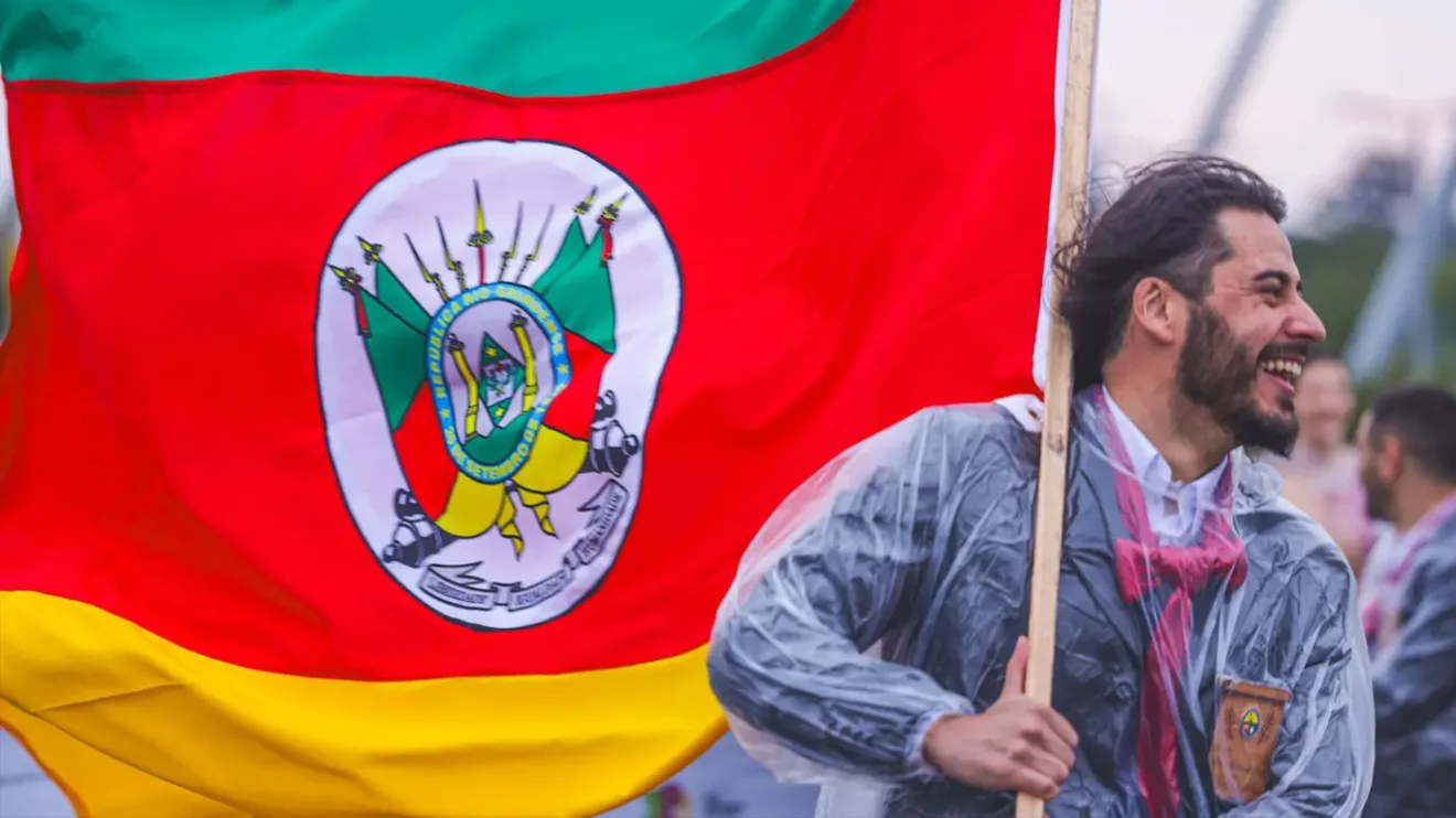 Foto de um homem segurando a bandeira do Rio Grande do Sul.